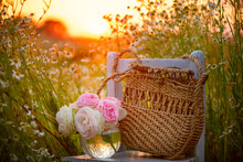 A Bouquet Of Garden Roses And A Wicker Straw Bag On An Old Chair In A Summer Garden At Sunset.