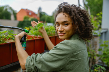 Female gardener is watering a plants in garden center. Concept of sustainability and growing organic