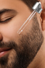 Poster - Man applying cosmetic serum onto face, closeup