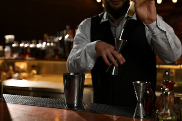 Poster - Bartender making fresh alcoholic cocktail at bar counter, closeup. Space for text