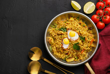 Tasty Rice With Meat, Eggs And Vegetables In Frying Pan Near Products On Black Textured Table, Flat Lay. Space For Text