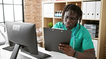 Sticker - African american man doctor using computer taking notes at the clinic