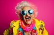 A jubilant senior woman, dressed in a colorful neon outfit, dons quirky sunglasses and showcases her extravagant style while sharing laughter and smiles in a trendy studio photoshoot.
