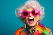 © Md Shahjahan - A jubilant senior woman, dressed in a colorful neon outfit, dons quirky sunglasses and showcases her extravagant style while sharing laughter and smiles in a trendy studio photoshoot.