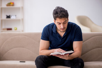 Sticker - Young male student reading book at home