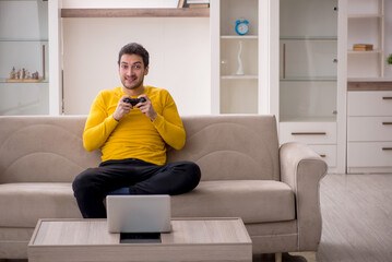 Wall Mural - Young man playing video games at home