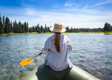 Woman Paddling On An Inflatable Raft While Floating The Snake River In Island Park, Idaho On An Adventure Vacation In The Great Outdoors. Near Yellowstone National Park
