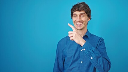 Poster - Young hispanic man smiling pointing to the side over isolated blue background