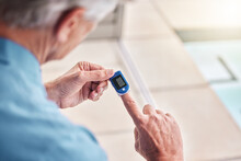 Closeup, digital oximeter and elderly hands measure oxygen saturation, pulse or heart health. Finger, blood test monitor and senior man in retirement home for healthcare, medical check and wellness