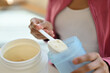 © Prathankarnpap - Young athletic woman pouring protein powder into a cup, drinking supplement for muscle after workout at home