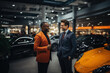 Portrait of a car dealer and a buyer standing among luxury cars