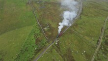 A High Angle Shot Of The Steam Train Riding In The Mountains.