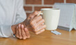 © chinnarach - close up senior woman hold on hand to relief shaky symptom while drink water for Parkinson’s disease and chronic illness health care concept