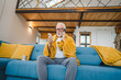 © Miljan Živković - one senior man sit on sofa bed hold thermometer check body temperature