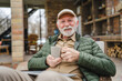 © Miljan Živković - One senior man sit outdoor in autumn day hold cup of coffee or tea