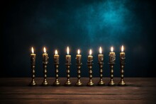 9 Chanukah / Hanukkah Candles In Separate Candle Holders Arranged Like In A Menorah On A Wooden Desk Against A Dark Blue Wall, Background With Copy Space For Display Or Mockup