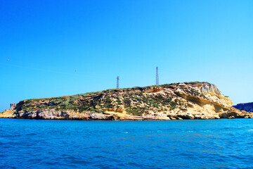 Wall Mural - Energizing view from Tremiti Islands (Isole Tremiti) in the Adriatic Sea at the balmy sandy colors of the rocky spur, interspersed with vegetation, technological towers, amongst creamy deep blue sea