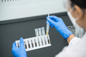 close up scientist wearing blue gloves working with test tube in the flume hood at laboratory.select