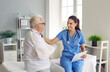 © Studio Romantic - Smiling doctor supporting elder patient with arm injury. Young woman in blue uniform scrubs together with old man with broken arm in sling sitting on medical bed and talking. Injury treatment concept