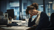An exhausted woman employee in office, siitting in front of paperload on desk.