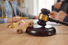 Small, Little Wooden Toy Car, Sound Block, Gavel And Scales Of Justice On Office Table, With People Talking In Background. Legal Services, Court, Law, Insurance, Accident Lawyer Concept