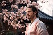© Andrii Zastrozhnov - A stylish and handsome young man enjoys the springtime beauty of cherry blossoms in a garden, exuding confidence and happiness.