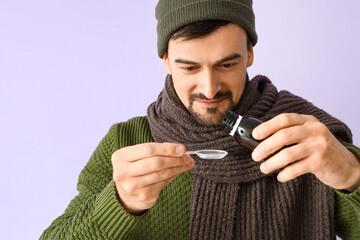 Sticker - Ill young man with cough syrup on lilac background, closeup