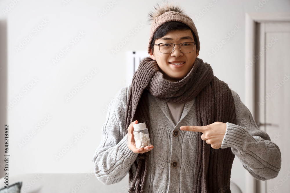 Ill Asian man with pill bottle at home