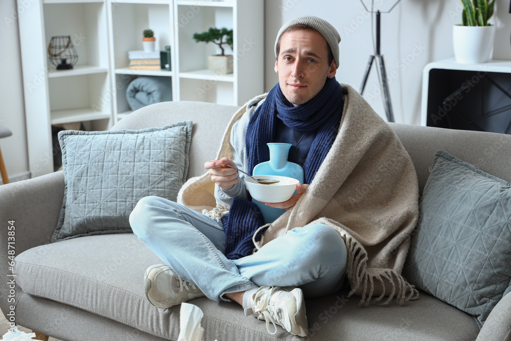 Ill young man eating soup at home