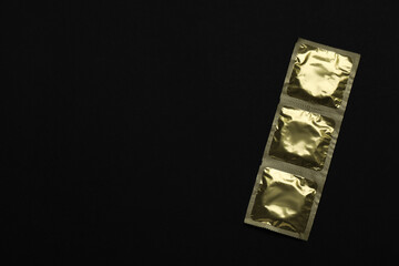 Condom packages on black background, top view and space for text. Safe sex
