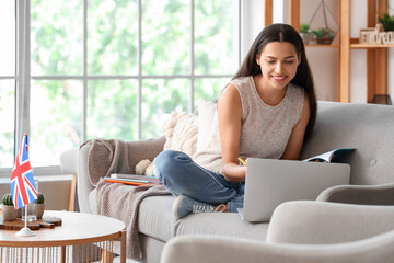 Wall Mural - Young woman with laptop learning English language online at home