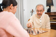 © sorapop - Smiling senior elderly having fun playing chess game with beautiful daughter at home, nurse caregiver in nursing home for leisure, Happy active retired people, Healthcare and medical homecare concept