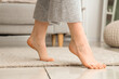 Barefoot woman with floor heating at home, closeup