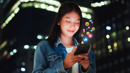 Young asian women watching live streaming video in the night city. Happy female using mobile smartphone social media application