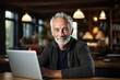 © Sergio - Senior and technology. Elderly caucasian man using laptop in coworking space, working in loft office and looking at camera