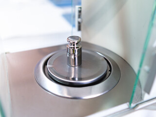 Wall Mural - Close-up of metal weight to calibrate on a balance in a laboratory.