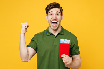 Poster - Traveler winner young man wears green casual clothes hold passport ticket isolated on plain yellow background. Tourist travel abroad in free spare time rest getaway. Air flight trip journey concept.