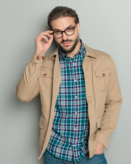 Canvas Print - confident sexy man with beard holding hands in pockets and fixing glasses