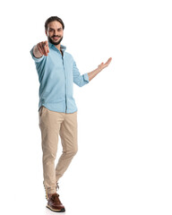Wall Mural - handsome casual man pointing finger forward while walking and inviting to side