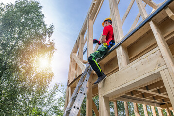 Wall Mural - Wooden Skeleton House Frame and the Contractor Worker.