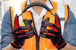Male worker with reflective orange vest and protective hand gloves holding yellow safety ear muffs or ear protectors preparing to wear on his head. Equipment for high noise reduction