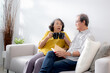 © NT_studio - Happiness senior couple sitting on sofa cheer coffee cup and drinking in living room at home, happy elderly man and woman sitting on couch drinking coffee and talking with cozy, bonding and relation.