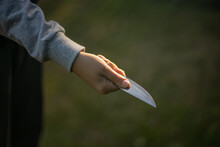 A Child's Hand With A Sharp Knife. Child Crime At School. The Knife Is In The Boy's Hand.