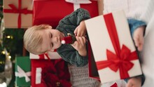 Adorable Blond Toddler Holding Elf Toy Of Christmas Gift Sitting On Floor At Home