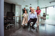 © Mediteraneo - Group of professional people racing with the chairs while on a break in the modern office