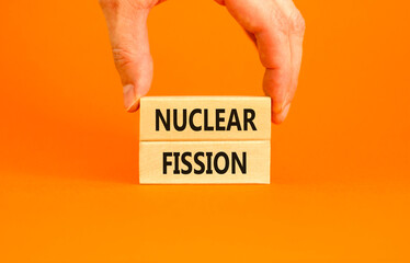 Wall Mural - Nuclear fission symbol. Concept words Nuclear fission on beautiful wooden blocks. Beautiful orange table orange background. Businessman hand. Business science nuclear fission concept. Copy space.