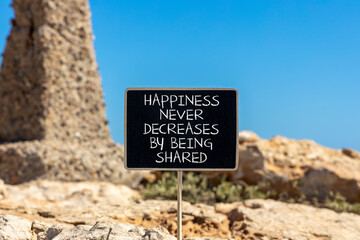 Happiness symbol. Concept words Happiness never decreases by being shared on beautiful black chalkboard. Beautiful stone blue sky background. Motivational Happiness concept. Copy space.