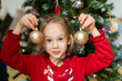 © ADDICTIVE STOCK - Girl with bauble against Christmas tree