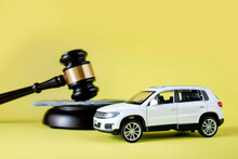 Car auction concept - gavel and car key on yellow background. Accident lawsuit or insurance, court case.