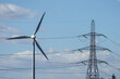 Wind turbine and electricity pylon on blue sky background
